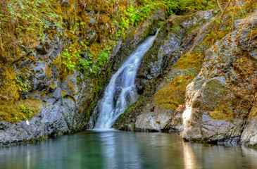 Gentle waterfall pours into a clean clear pool of water in Rogue River Oregon