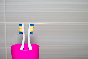 Toothbrushes in a plastic glass closeup. Copy space Concepts: hygiene, family relationships, quarrel, disagreement, resentment.