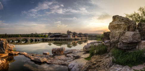 Panorama sunset with blue sky and orange clouds, a castle and a bridge reflected in the water....