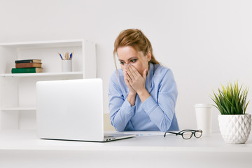Exited woman surprised by something watching her laptop at office
