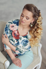 Naklejka premium portrait of a beautiful young woman with blond curly curls tender elegant girl with expressive blue eyes in the studio. Fashion photo