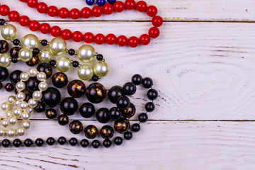 Different beads necklaces on white wooden background