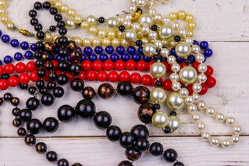 Different beads necklaces on white wooden background