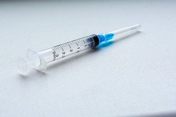 Syringe for injection on a white background. Selective focus. Copy space. Concept: drug addiction, vaccination, emergency medical care.