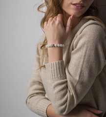  bracelet made of moonstoneis on the hand, on the arm is a bracelet made of white stones, girl on white background