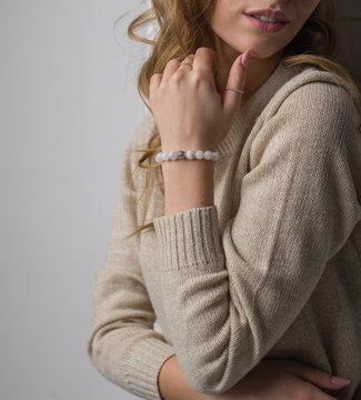  bracelet made of moonstoneis on the hand, on the arm is a bracelet made of white stones, girl on white background
