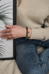 jade bracelet on the hand of the girl, the girl is sitting on the bed, the girl is holding a picture with foliage.