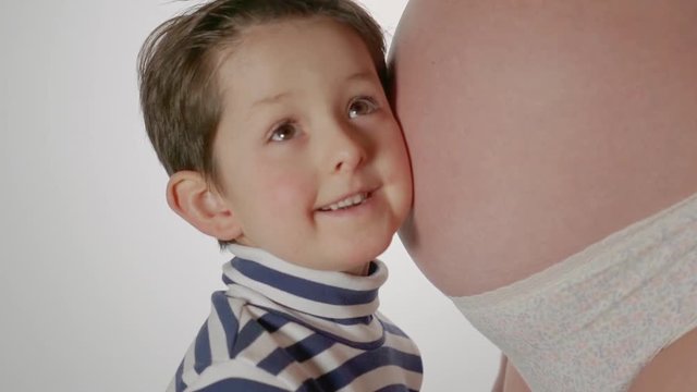 Little boy hugging mother's pregnant belly