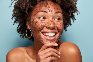 Natural beauty, spa and healthy skin concept. Glad African American woman peels skin with coffee...