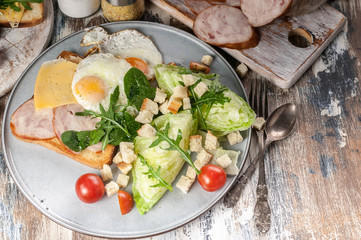 Healthy breakfast and snacks. Fried eggs, chicken ham sandwich, ice salad, cherry tomatoes and arugula.