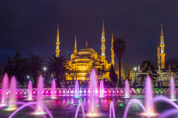 Fototapeta na wymiar fountain with blue illumination on Sultanahmet square in front of the Blue mosque (Sultan Ahmed Mosque)in Istanbul in the evening