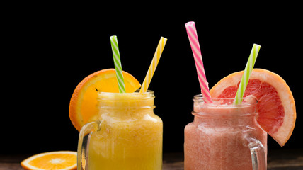 Glasses of fruit smoothie with Pink Grapefruit and orange. Dark background.