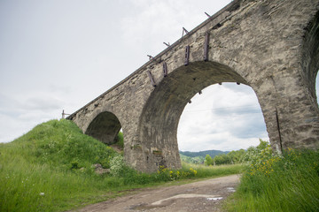 Fototapeta premium Old stone railroad bridge among fir trees