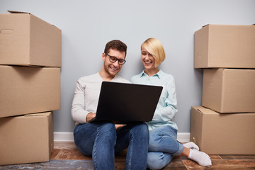 Happy young couple moving and using laptop 