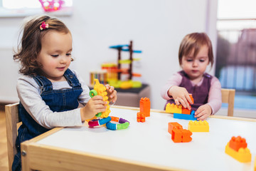 Children toddlers girls play toys at home, kindergarten or nursery.