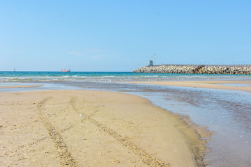 Stone breakwater, sandy beach, blue sea. Ashdod, Israel