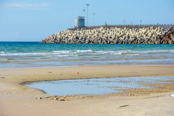 Stone breakwater, sandy beach, blue sea. Ashdod, Israel