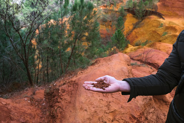 Tourist Provence. Roussillion. Ocher canyon. Man's hand with clay red. Close-up.