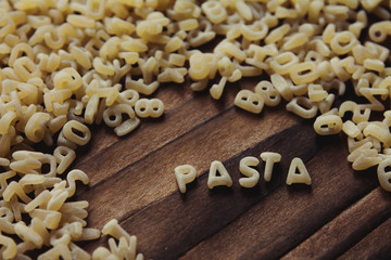 wooden background with pasta, alphabet, word 