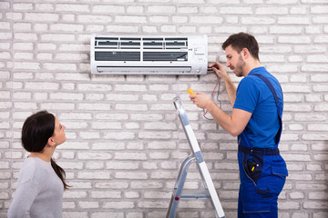 Technician Repairing Air Conditioner With Digital Multimeter