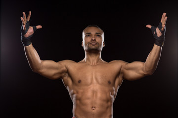 Fototapeta na wymiar Muscular shirtless male fighter on black background