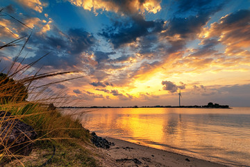 Renewable energy with wind turbines at the sea in sunset