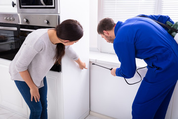 Worker Spraying Insecticide Chemical At Kitchen