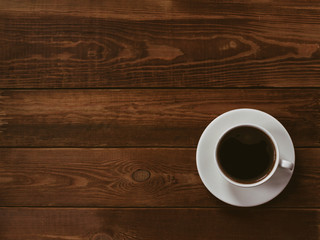 Cup of black coffee on a brown wooden background. Author processing, film effect, low key.