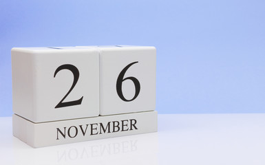 November 26st. Day 26 of month, daily calendar on white table with reflection, with light blue background. Autumn time, empty space for text