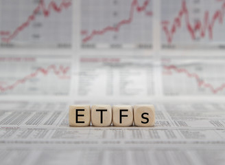 ETF exchange trades funds word on a blurred business newspaper