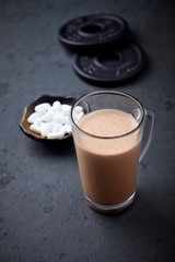 Chocolate Protein Shake, BCAA amino acids and plates. Nutrition for bodybuilding. Black stone background. Copy space.