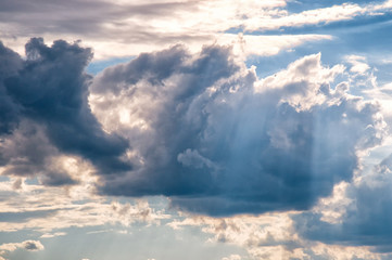 Fototapeta na wymiar Moody grey blue clouds in sky with rays of sun