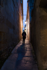 A person crossing a narrow street in Cordoba, Spain