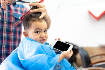Cute Boy Getting a Hair Cut in a Barber Shop. Beauty Concept.