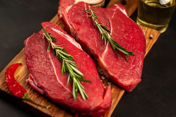 raw new york steak with ingredients on a cutting board. on the background of dark stone.