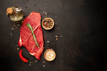A big raw New York steak with ingredients. on the background of dark stone.