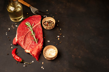 A big raw New York steak with ingredients. on the background of dark stone.