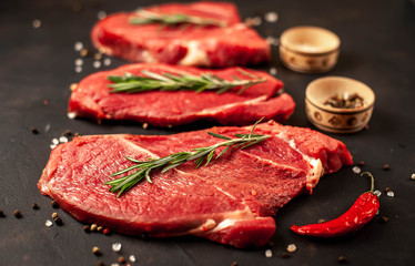 big raw new york steaks with ingredients. on the background of dark stone.