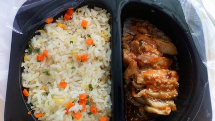 Rice and baked chicken meat Packed in a black plastic container There is a plastic cover for heating food.