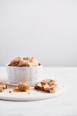 Traditional Chtristmas gingerbread cookies made of ginger, honey and cinnamon with icing in bowl on white marble table over white background. Copy space for text.