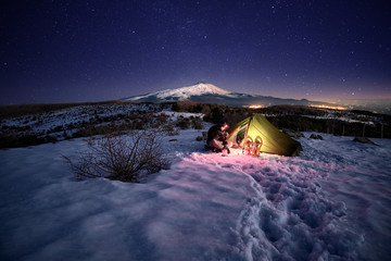 Man Near Illuminated Tent On The Snow Under Starry Sky