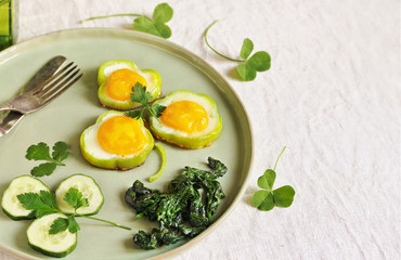 green breakfast on St. Patrick's Day. eggs in the form of clover. Fried Eggs Shamrock  in Green Pepper rings with Braised Spinach. parsley leaves like clover leaves.