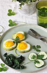 green breakfast on St. Patrick's Day. eggs in the form of clover. Fried Eggs Shamrock  in Green Pepper rings with Braised Spinach. parsley leaves like clover leaves.