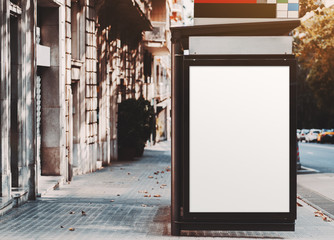 A poster placeholder inside of city bus stop near the road; vertical blank advertising banner mock-up on the pavement stone; white empty information billboard inside of public transport stop in Spain