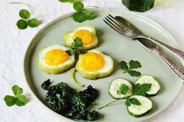 green breakfast on St. Patrick's Day. eggs in the form of clover. Fried Eggs Shamrock  in Green Pepper rings with Braised Spinach. parsley leaves like clover leaves.