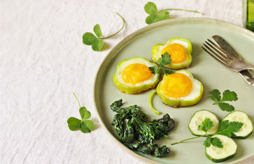 green breakfast on St. Patrick's Day. eggs in the form of clover. Fried Eggs Shamrock  in Green Pepper rings with Braised Spinach. parsley leaves like clover leaves.