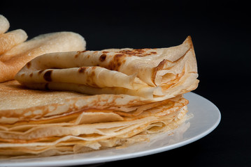 Pancakes, pancakes on a plate, dark background.