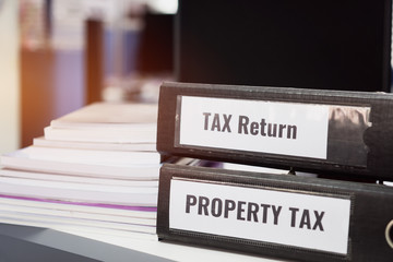 Property tax and tax return word on folders stack with label black binder on paperwork documents summary report in busy offices. HR-human resources business bookkeeping accountancy Document Concept