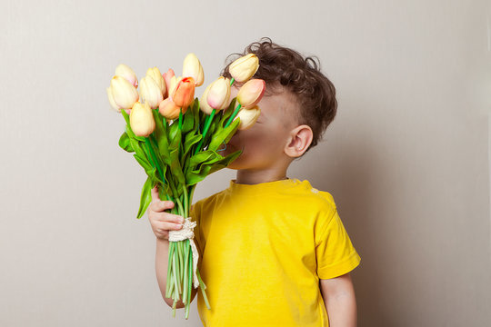 Boy Sniffs A Bouquet Of Tulips Gift For Mom. No Visible Face. Studio