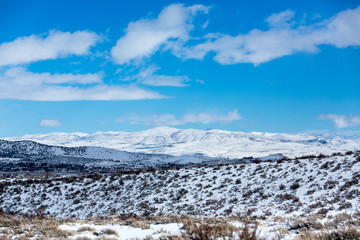 Fototapeta na wymiar Snow covered desert landscape with puffy clouds and blue sky